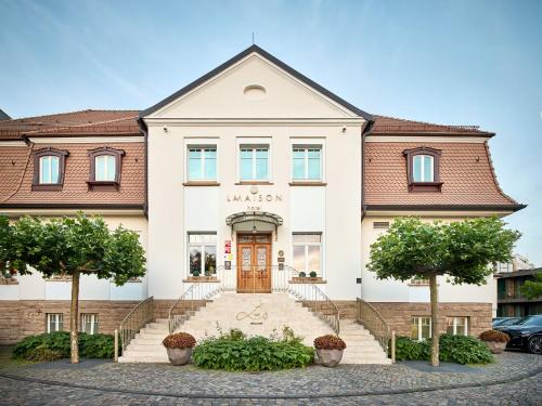 a large white building with a red door at LA MAISON hotel & spa in Saarlouis