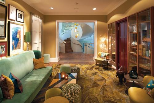 a living room with a green couch and a staircase at LA MAISON hotel & spa in Saarlouis
