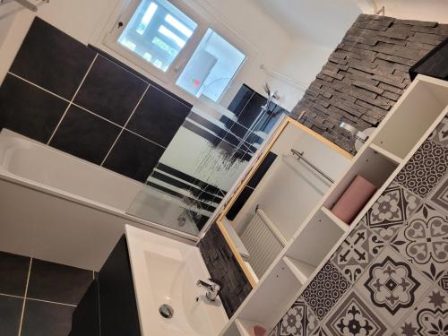 La salle de bains est pourvue de carrelage noir et blanc et d'une baignoire. dans l'établissement Appartement t3 privatif 56m2 La Baule proche mer, à La Baule