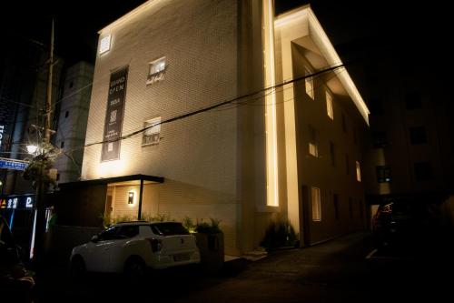 a white car parked in front of a building at night at Yeobaek Hotel in Incheon