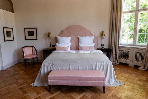 a bedroom with a large bed with a pink headboard at Schlosshotel Neustrelitz in Neustrelitz