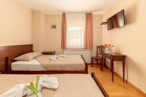 a hotel room with two beds and a desk at Guest House Pod Slavnikom in Podgorje