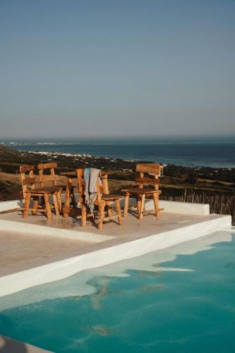 a picnic table and chairs next to a swimming pool at Ghar El Melh Outdoors in Raʼs al Jabal