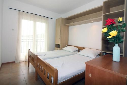 a bedroom with two beds and a vase of flowers at Waterfront Apartments in Tisno