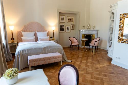 a bedroom with a bed and chairs and a fireplace at Schlosshotel Neustrelitz in Neustrelitz