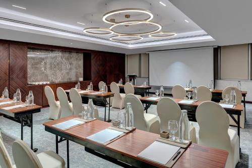 a conference room with tables and chairs and a projection screen at Movenpick Hotel Centaurus Islamabad in Islamabad