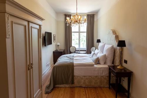 a bedroom with a bed with a chandelier and a window at Schlosshotel Neustrelitz in Neustrelitz