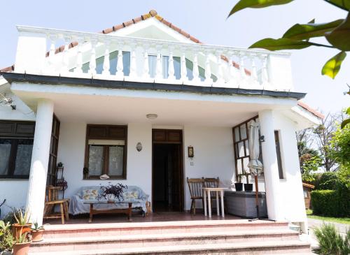 een wit huis met een veranda met een tafel bij Casa Nina in Somo