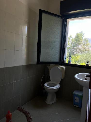 a bathroom with a toilet and a window and a sink at Holiday home in Vlorë