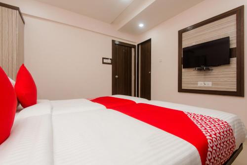 a bedroom with a red and white bed and a flat screen tv at Hotel O Gems in Turambhe