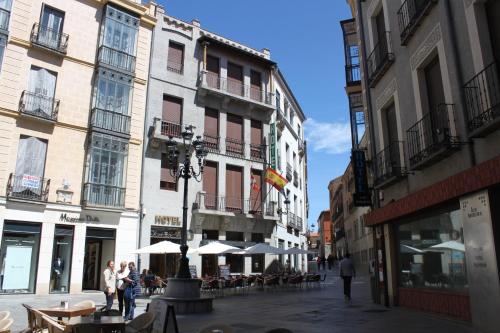 a city street with tables and umbrellas and buildings at Hotel Rey Niño in Ávila