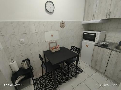 a small kitchen with a table and a clock on the wall at Centar Novi Sad in Novi Sad