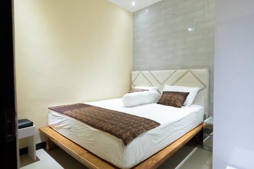 a bedroom with a bed with white sheets and brown pillows at Newly furnished small balinese house quiet area in Perean