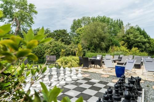a chess board and chairs in a garden at Le Manoir De La Poterie & Spa in Cricquebœuf