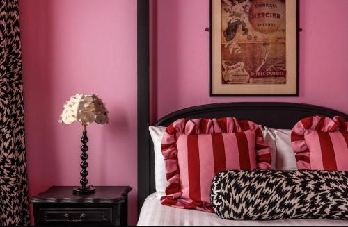 a bedroom with pink walls and a bed with a lamp at White Hart Hotel in Dorchester on Thames