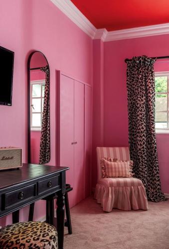 a pink room with a dressing table and a chair at White Hart Hotel in Dorchester on Thames