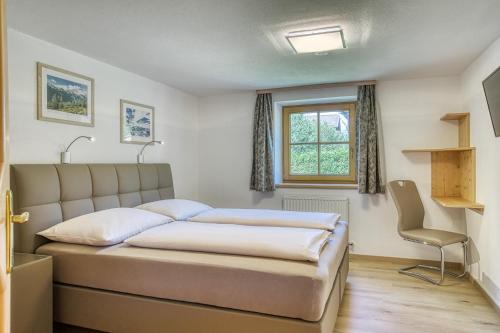 a bedroom with a bed and a window and a chair at Haus St. Bernard in Pettneu am Arlberg