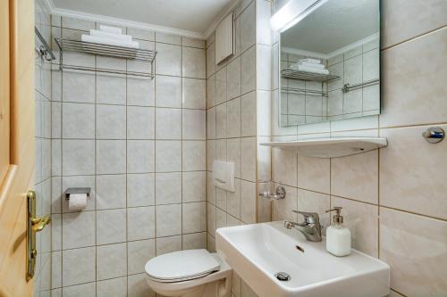 a bathroom with a sink and a toilet and a mirror at Haus St. Bernard in Pettneu am Arlberg