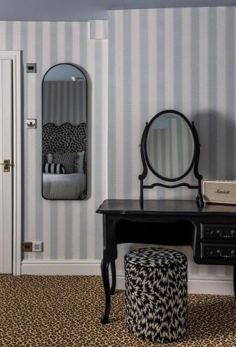 a vanity with a mirror and a table with a stool at White Hart Hotel in Dorchester on Thames