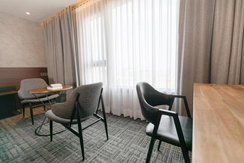 a hotel room with chairs and a table and a window at With Stay Jeju Hotel in Jeju