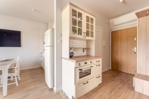 a kitchen with a white refrigerator and a table at Sunset Resort VI, Nadmorska 98A in Grzybowo