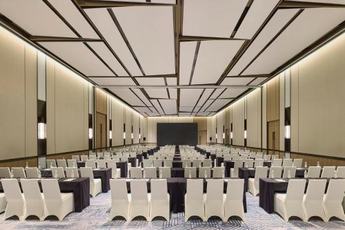 Habitación grande con filas de sillas y pantalla en Four Points by Sheraton Qingdao, Chengyang East, en Qingdao
