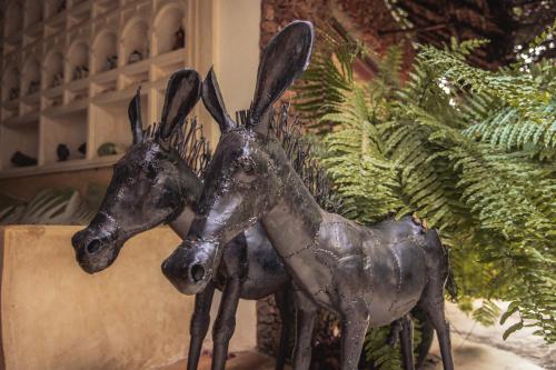 a metal statue of two deer standing next to a plant at Banana House and Wellness Centre in Lamu