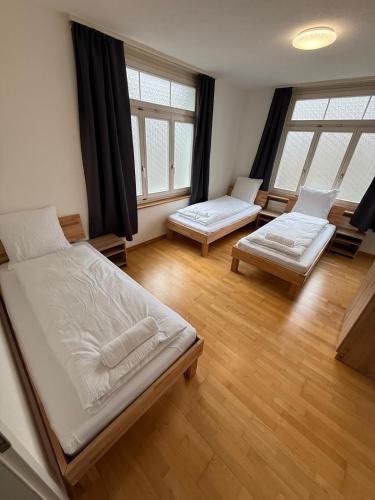 a bedroom with two beds and two windows at Swiss Holidays-City Apartments Interlaken in Interlaken