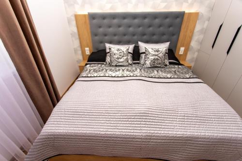 a bedroom with a bed with a headboard and pillows at 1-Bedroom LUX Apartment with Balcony & Underground Parking Garage in Spišská Nová Ves