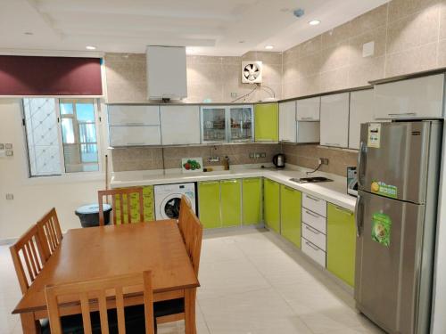 a kitchen with green and white cabinets and a wooden table at فلل الكناري in Taif