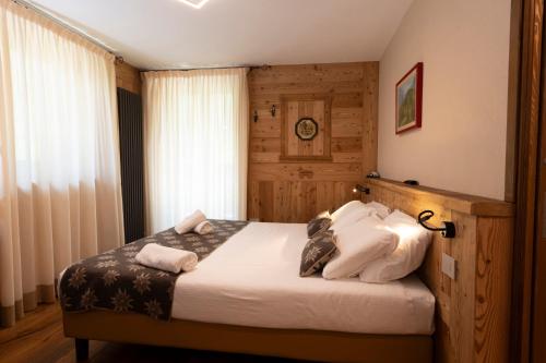 a bedroom with a bed with white sheets and pillows at Hotel Granta Parey in Rhêmes-Notre-Dame