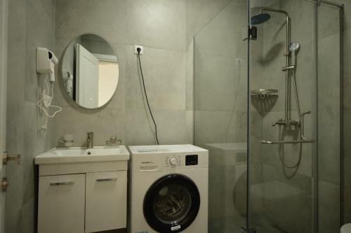 a bathroom with a washing machine and a shower at Thom Tower in Gonio