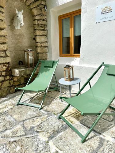 two green chairs and a table in front of a building at Château De La Bûcherie in Saint-Cyr-en-Arthies