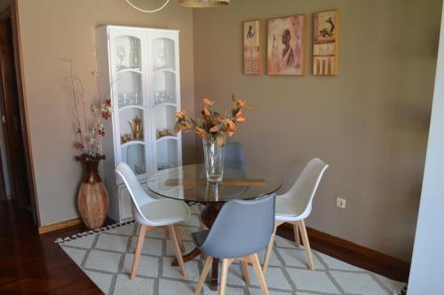 a dining room table with chairs and a vase with flowers at Coqueto Duplex en Vilagarcía de Arousa centro in Vilagarcia de Arousa