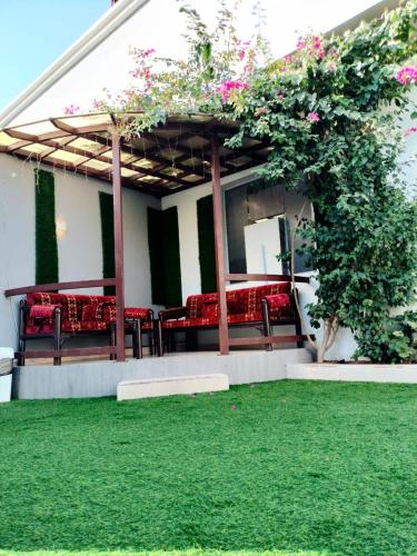 a patio with red cushioned chairs and a green lawn at فلل الكناري in Taif