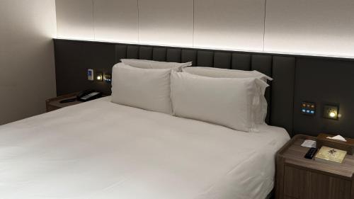 a large bed with white pillows and a black headboard at Talmud Hotel Classic Taiwan Boulevard in Taichung