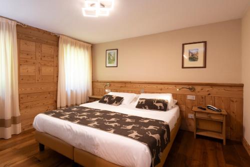 a bedroom with a large bed and a wooden wall at Hotel Granta Parey in Rhêmes-Notre-Dame