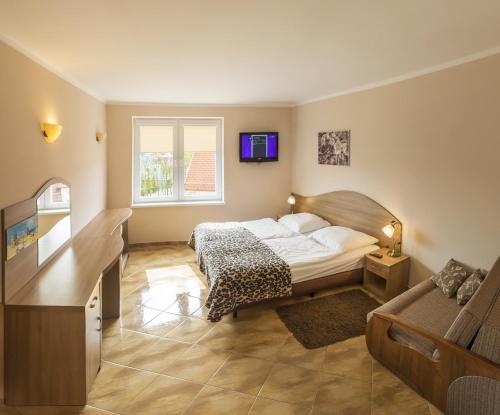 1 dormitorio con 1 cama, TV y sofá en Apartamenty Rok, en Kołobrzeg