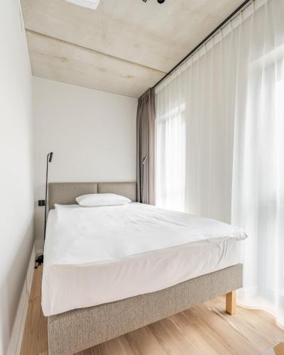 a bedroom with a bed with white sheets and a window at Noli Gdansk Old Town in Gdańsk
