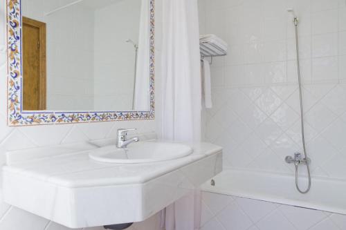 Baño blanco con lavabo y espejo en Hotel Rey Niño, en Ávila