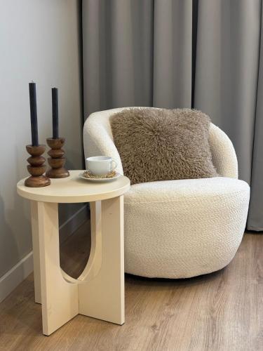 a living room with a chair and a side table at TINTURA by BAST - Wanna, Antresola, OFF Piotrkowska, EC1 ,Stajnia Jednorożca, Winda, Parking na Terenie, Orientarium, Hopa Lupa, ATLAS ARENA in Łódź