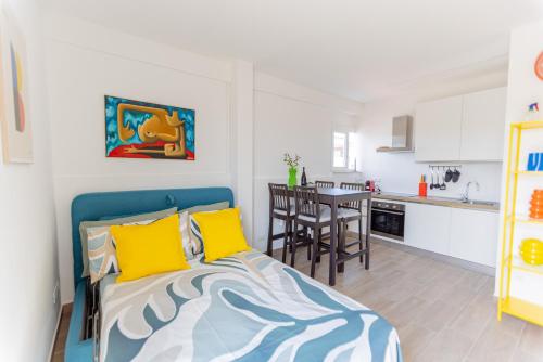 a bedroom with a bed with yellow pillows and a kitchen at Il tuo rifugio vista mare DIMORA SABUCCHI in Pescara