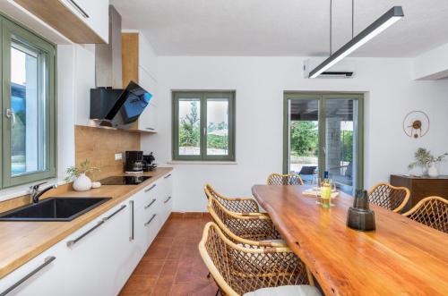 a kitchen with a wooden table and chairs at Villa Philia by Villsy in Butkovići