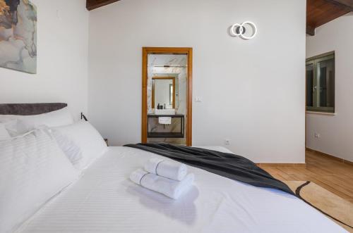 a white bed with a pair of towels on it at Villa Philia by Villsy in Butkovići