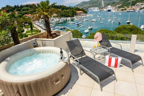 una bañera de hidromasaje en un patio con sillas y vistas al puerto en Adriatic Deluxe Apartments, en Dubrovnik