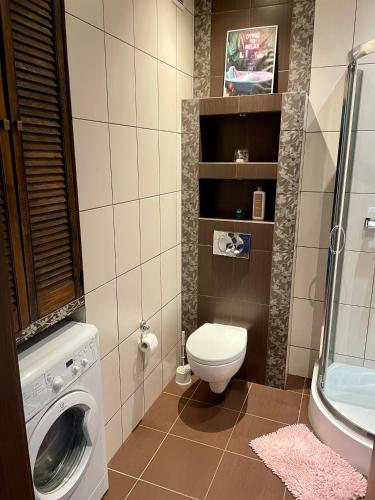 a bathroom with a toilet and a washing machine at Apartament Lipowa in Kalisz