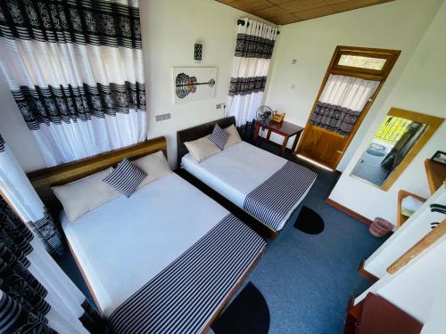 two beds in a room with curtains at 360 City View in Badulla
