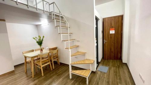 a room with a table and a spiral staircase at Era Apartment Khuc Thua Du in Hanoi