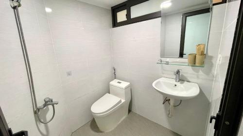 a white bathroom with a toilet and a sink at Era Apartment Khuc Thua Du in Hanoi