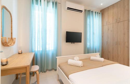 a bedroom with a bed and a desk and a television at Sea & Salt Boutique Apartment 4 in Finikounta